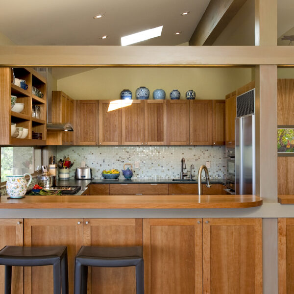 Broadview kitchen remodel with cherry cabinetry, a curved wood bar counter with two stools, a glass mosaic tile backsplash, and a skylight