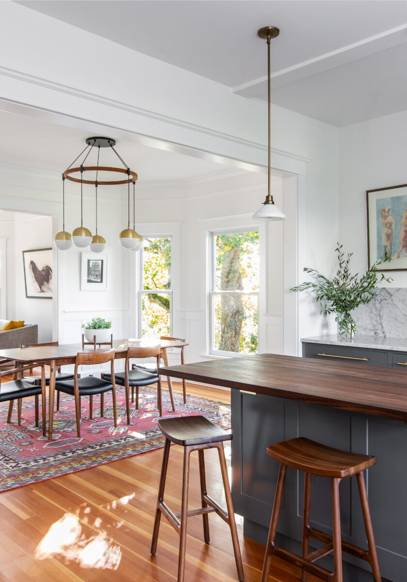 Miller Park kitchen with a wood-topped island opening to a dining room with a brass chandelier in a turn-of-the-century home