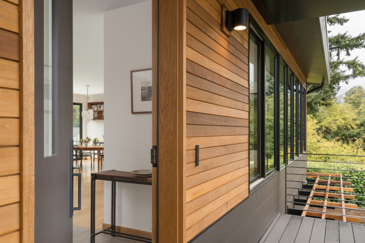 Wood-clad exterior wall and glass door opening from a North Beach home onto a deck