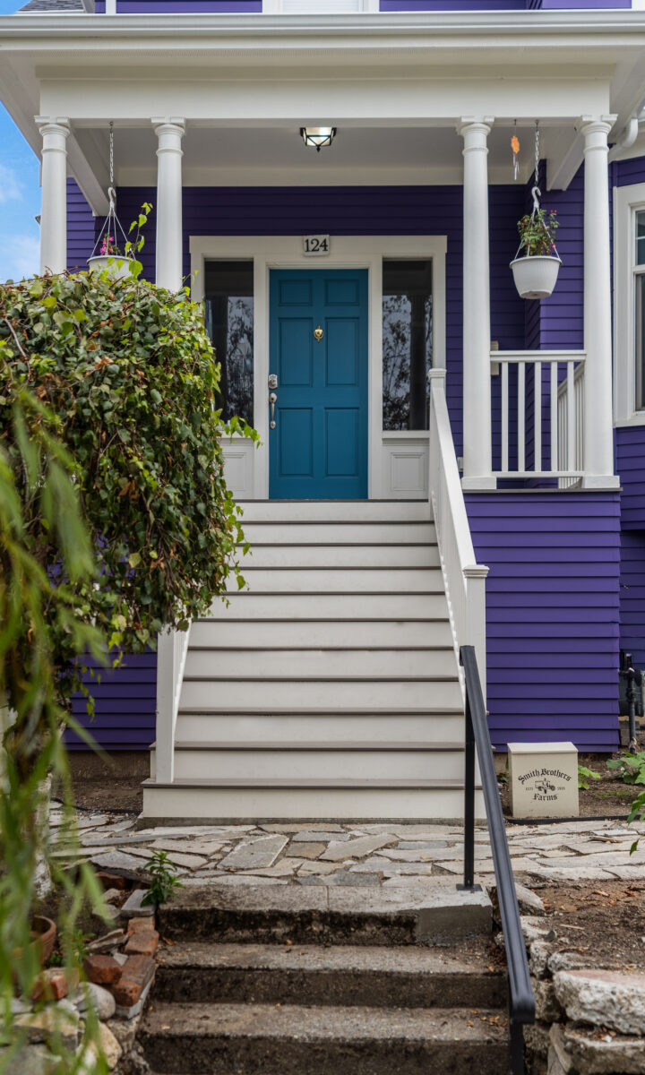 Leschi century-old home with purple siding, a teal front door, and a new covered front porch with white railings and stairs