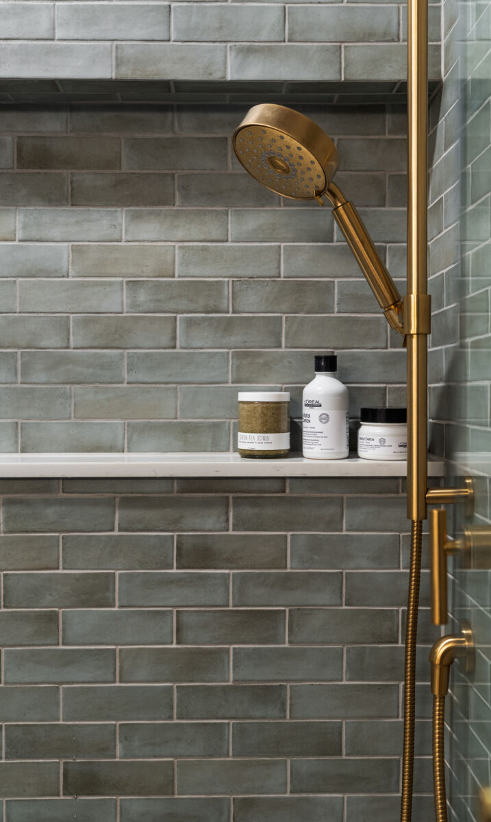 Gray-green tile shower with brass fixtures and a built-in ledge in a Cherry Hill bathroom