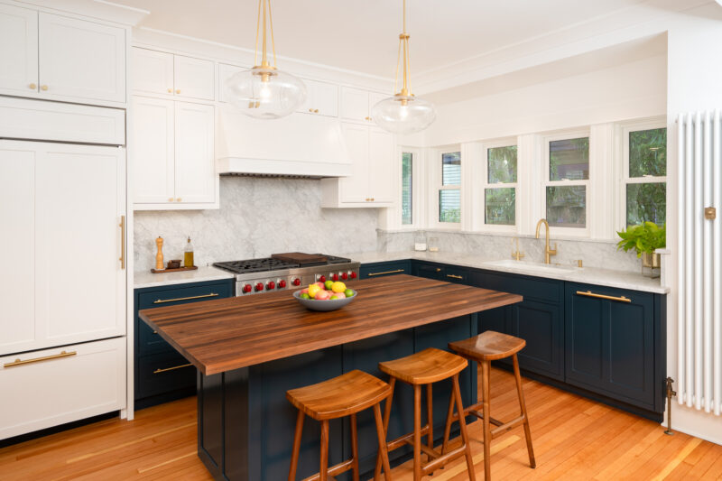 Capitol Hill kitchen with white upper cabinets, a range wall with marble backsplash, and a walnut island with three stools