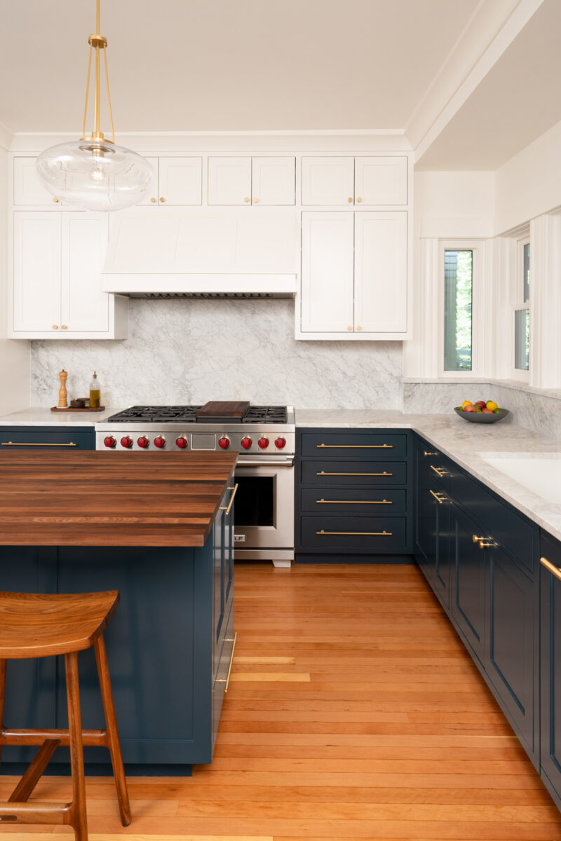 Capitol Hill kitchen with a professional range, white cabinetry, marble backsplash, and a navy island with a walnut top