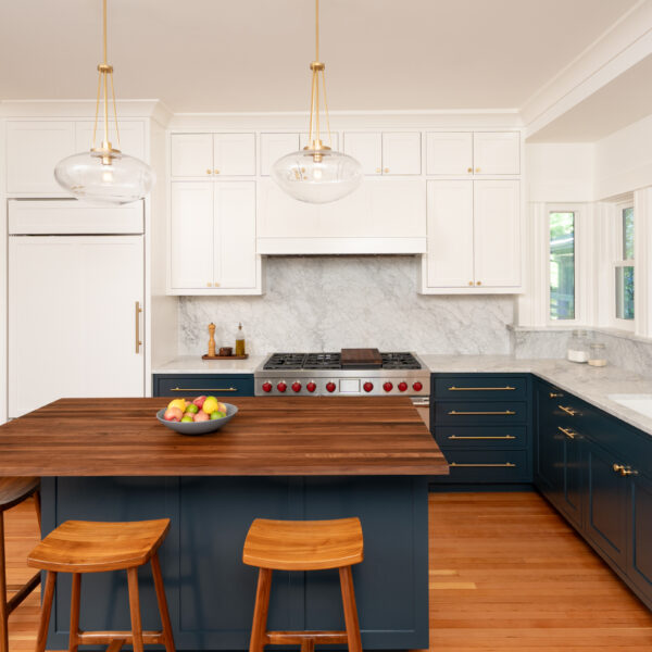 Capitol Hill kitchen with navy lower cabinets, a walnut-topped island with wood stools, and marble backsplash in a 1901 home