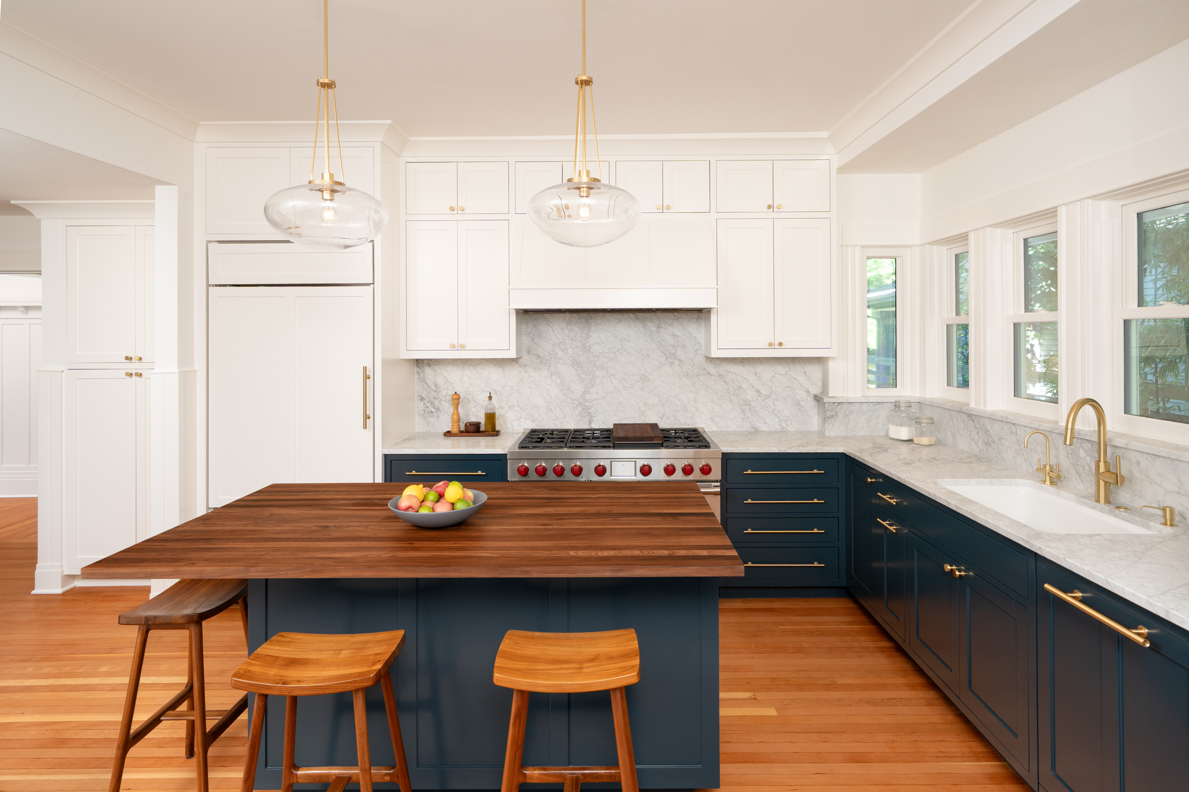 Capitol Hill kitchen with navy lower cabinets, a walnut-topped island with wood stools, and marble backsplash in a 1901 home