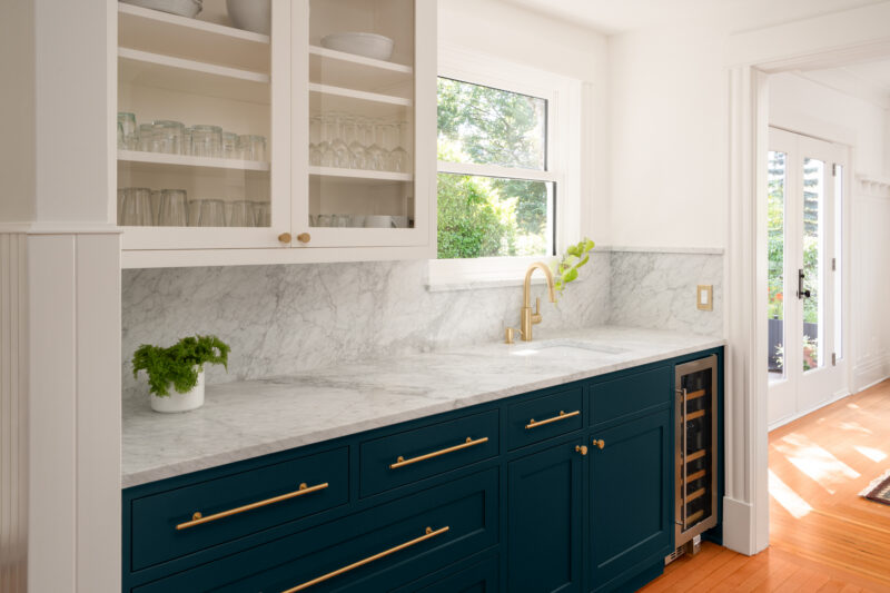 Capitol Hill beverage station with glass-front upper cabinets, marble counters, and a wine fridge in navy cabinetry