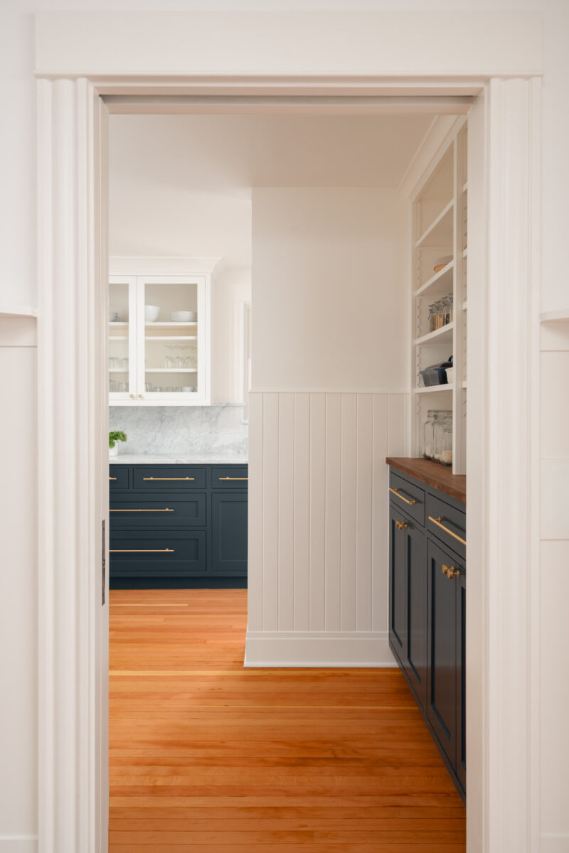 View through a doorway into the Capitol Hill pantry with navy cabinets and open shelving