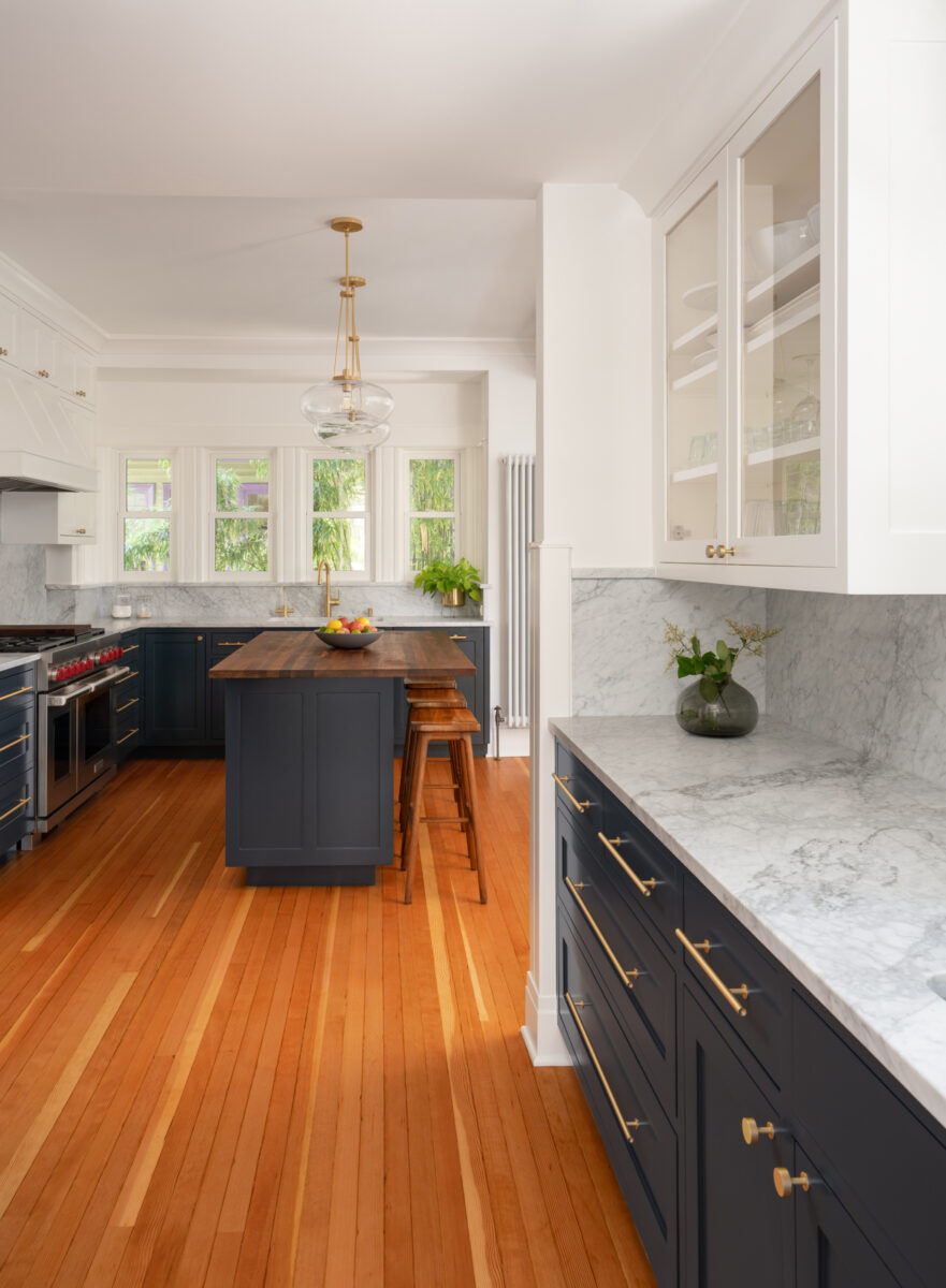 Capitol Hill kitchen looking toward the walnut island and window wall, with navy cabinets, marble counters, and fir floors
