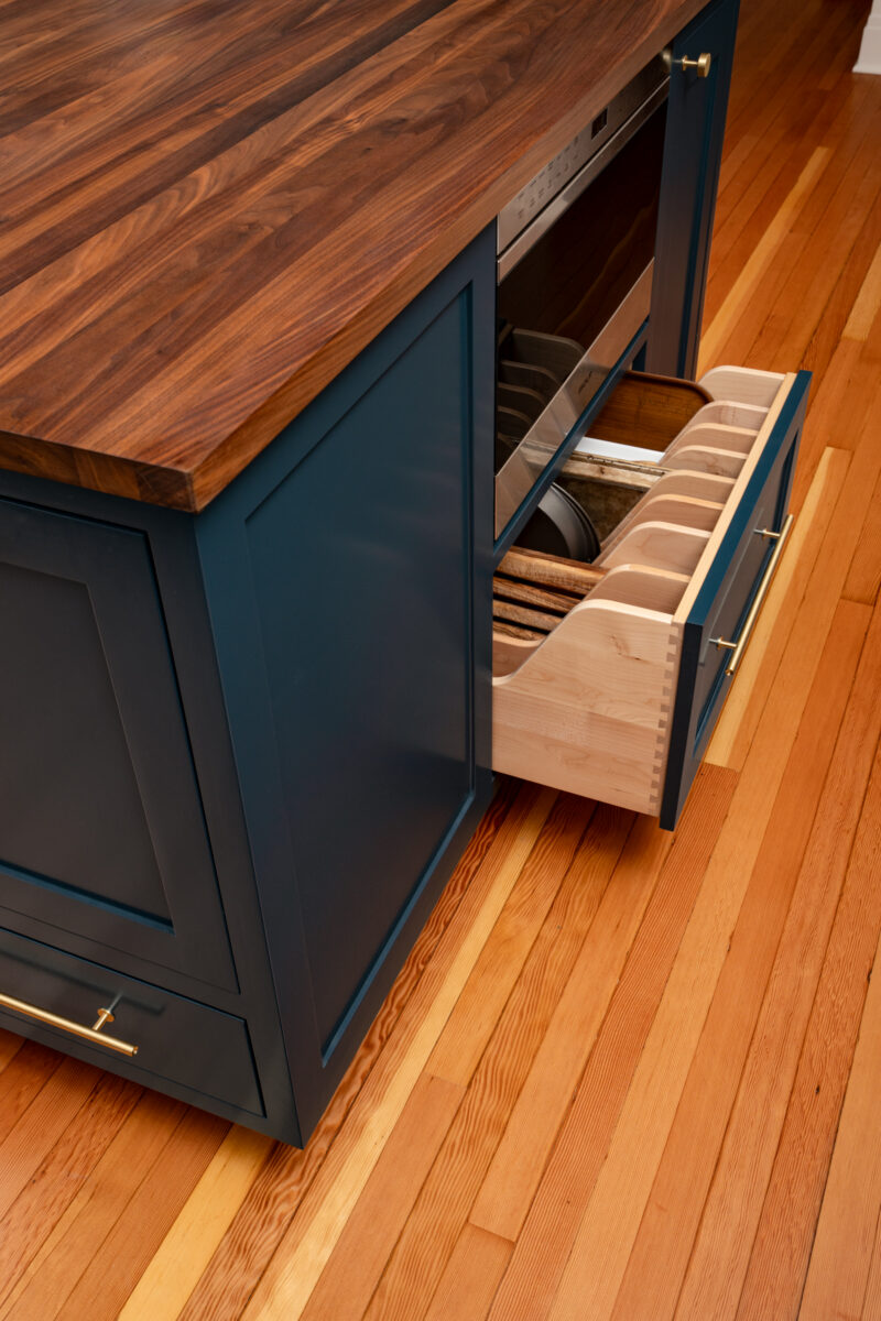 Navy island base with a pull-out drawer of wood dividers below a walnut countertop in a Capitol Hill kitchen