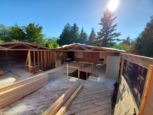 Construction photo of North Beach roof removal with stacked lumber on the open subfloor
