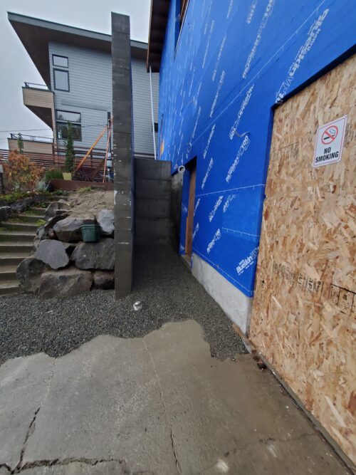 Construction photo of house wrap and a new stone clad wall along the North Beach entry stairs