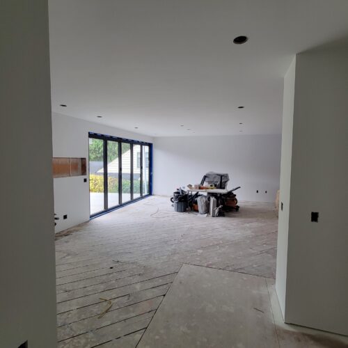 Construction photo of the North Beach main floor after drywall with glass doors to the patio